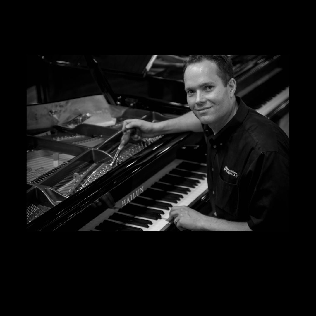 Brigham Larson at Brigham Larson Pianos piano showroom tuning a grand Hailun Piano in polished black.