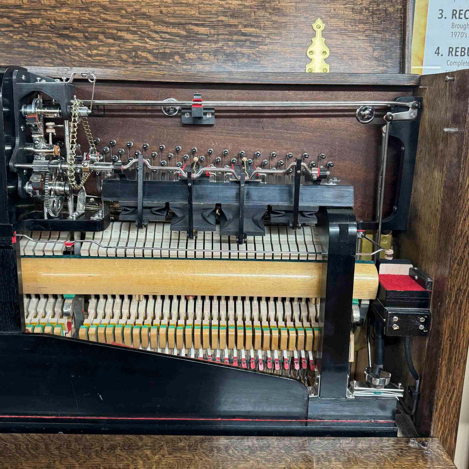 Close-up of a fully restored 1913 Whitney upright piano player mechanism inside a wooden cabinet  at Brigham Larson Pianos in Orem, Utah piano heirloom piano restoration shop.