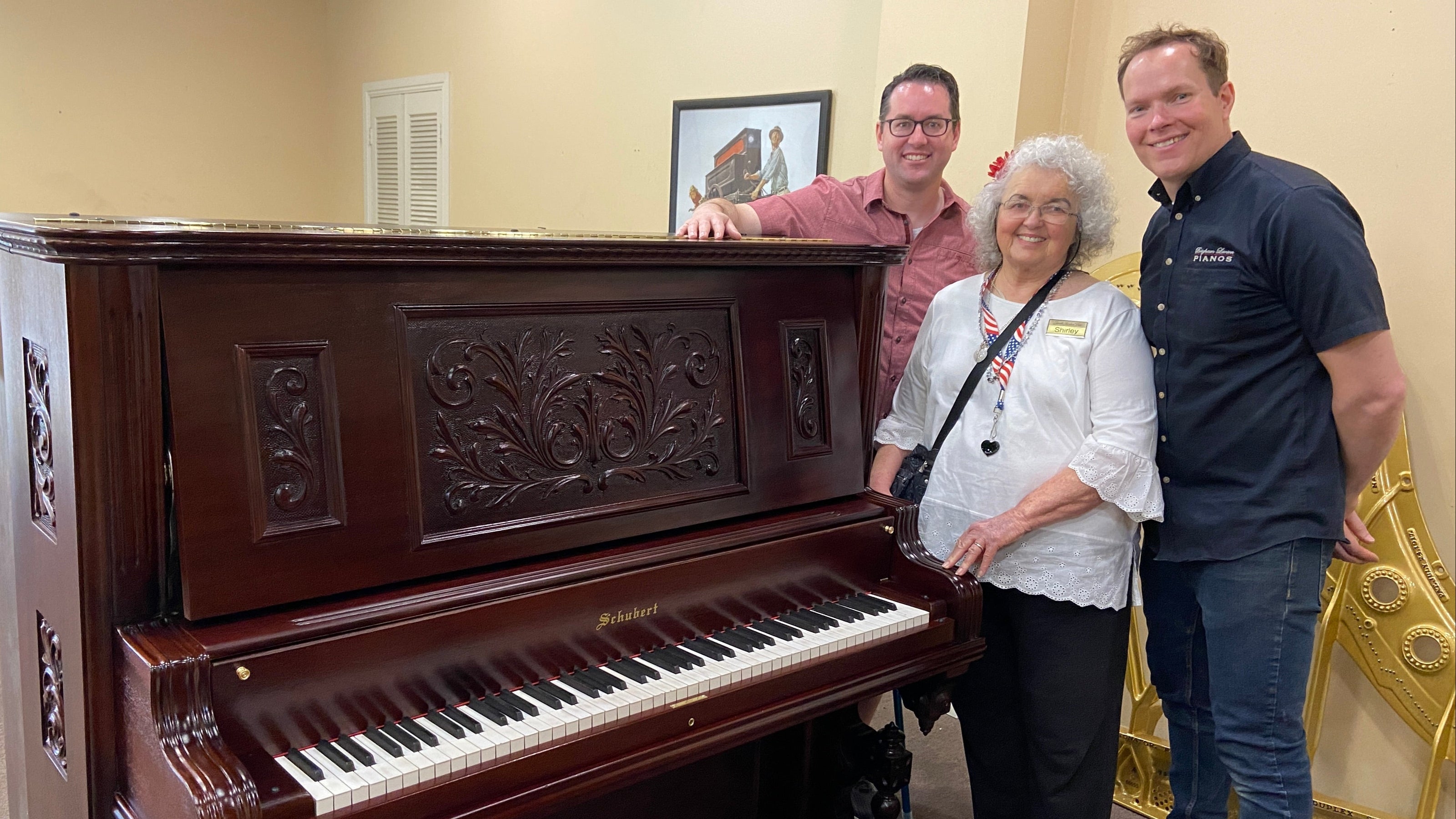 Brigham Larson with happy heirloom piano restoration family unveiling their Schubert Upright restored family heirloom piano for the first time after full restoration and refinishing at Brigham Larson Pianos family heirloom piano restoration shop in Orem, UT. 