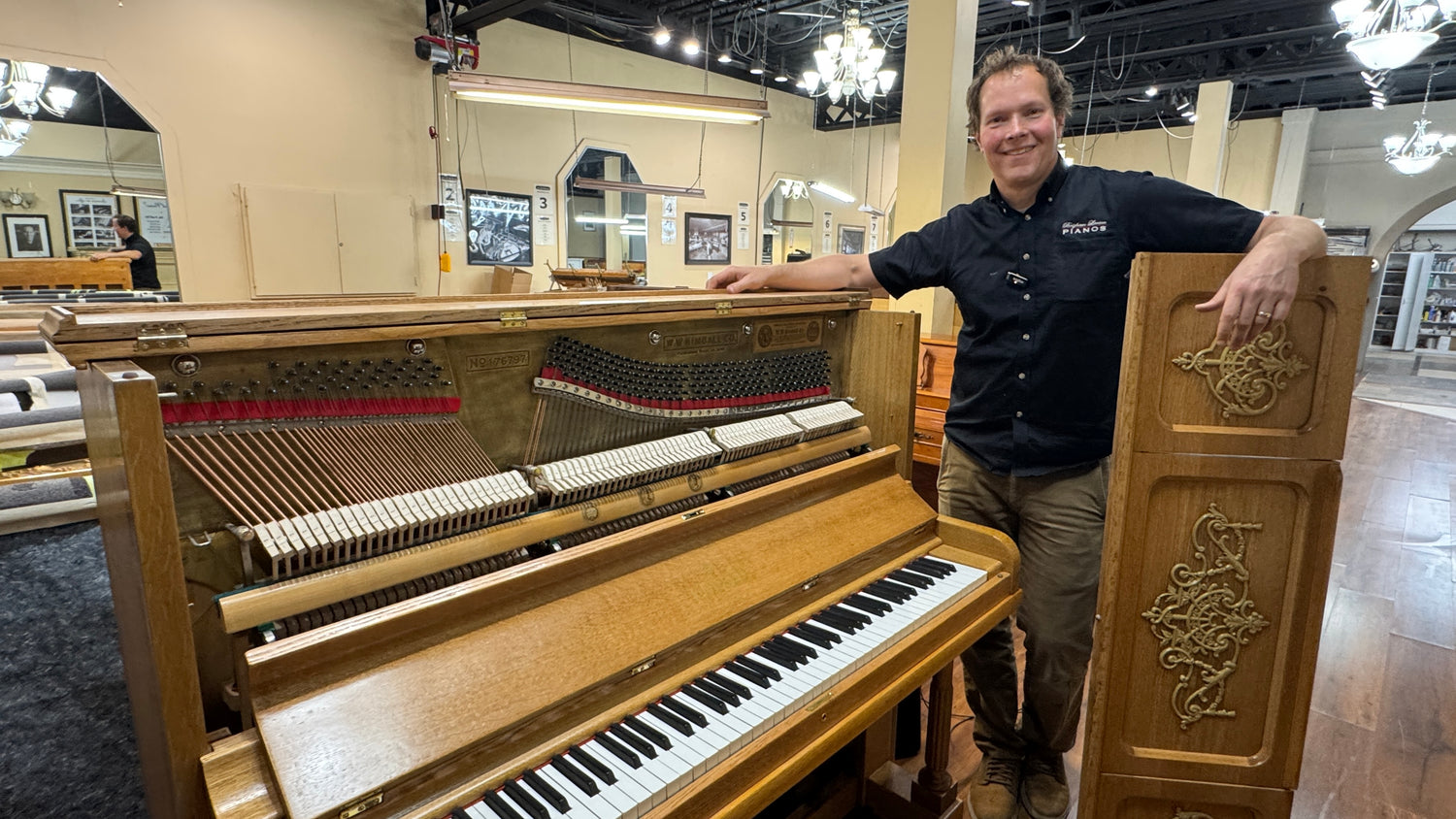 Brigham Larson standing next to a piano in a showroom setting