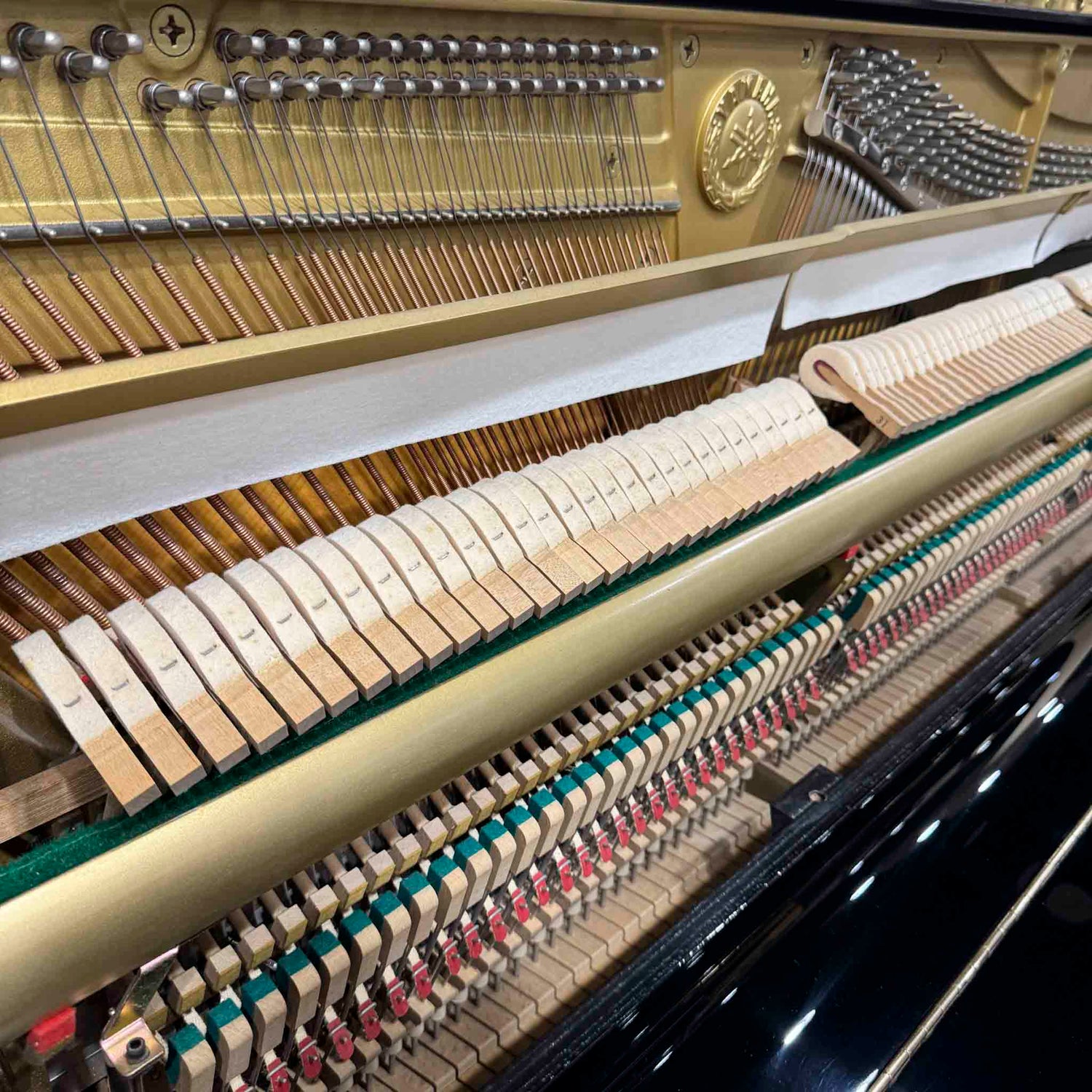 Close-up of a Yamaha U1 upright piano's internal mechanism with strings and keys.