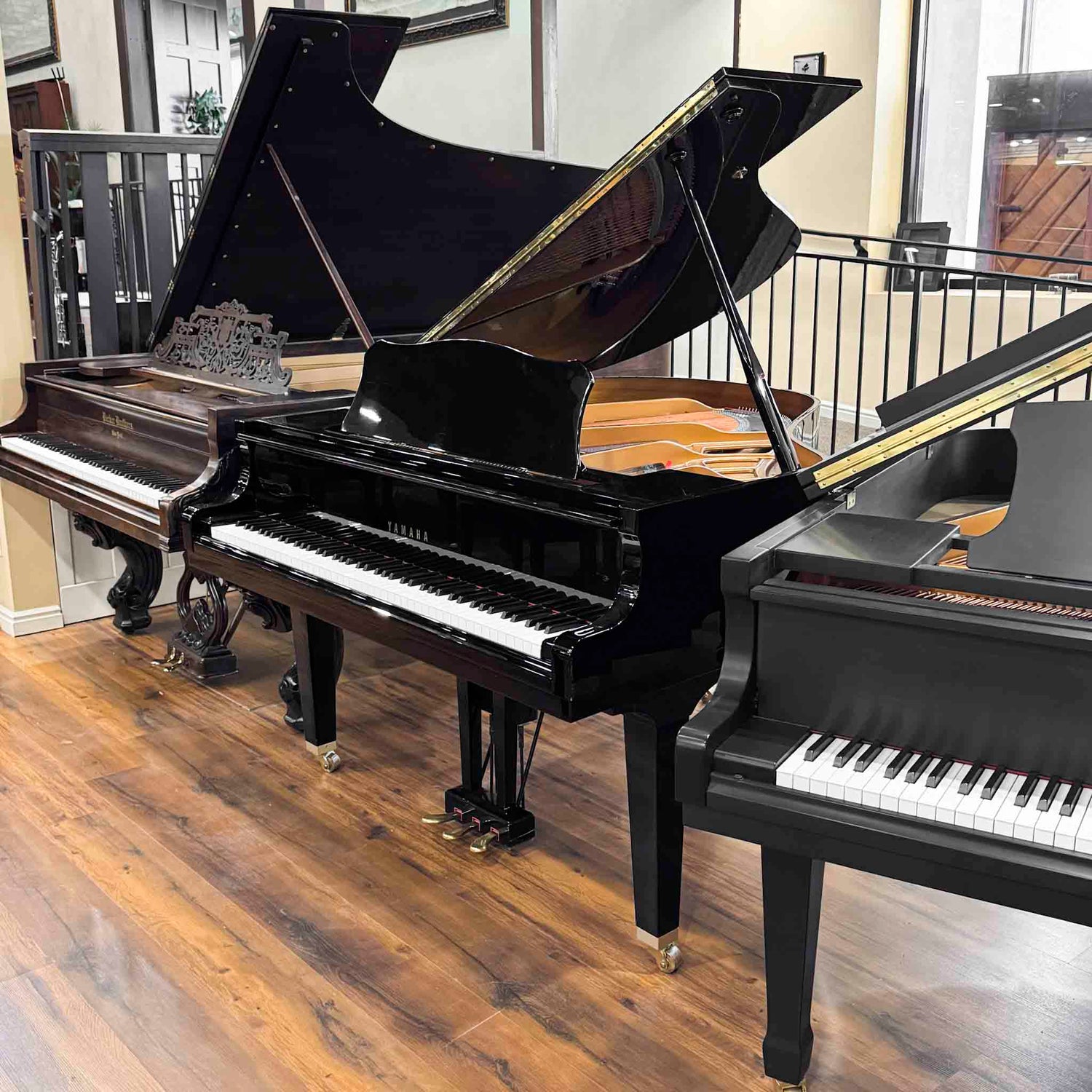 A polished black Yamaha DGP1 baby grand player piano with brass trim displayed in a showroom.
