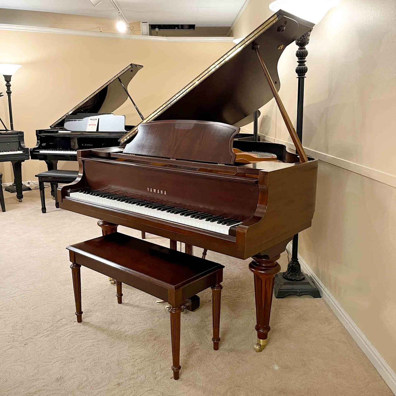 Wooden Yamaha GB series grand piano in a room with beige walls and carpet.