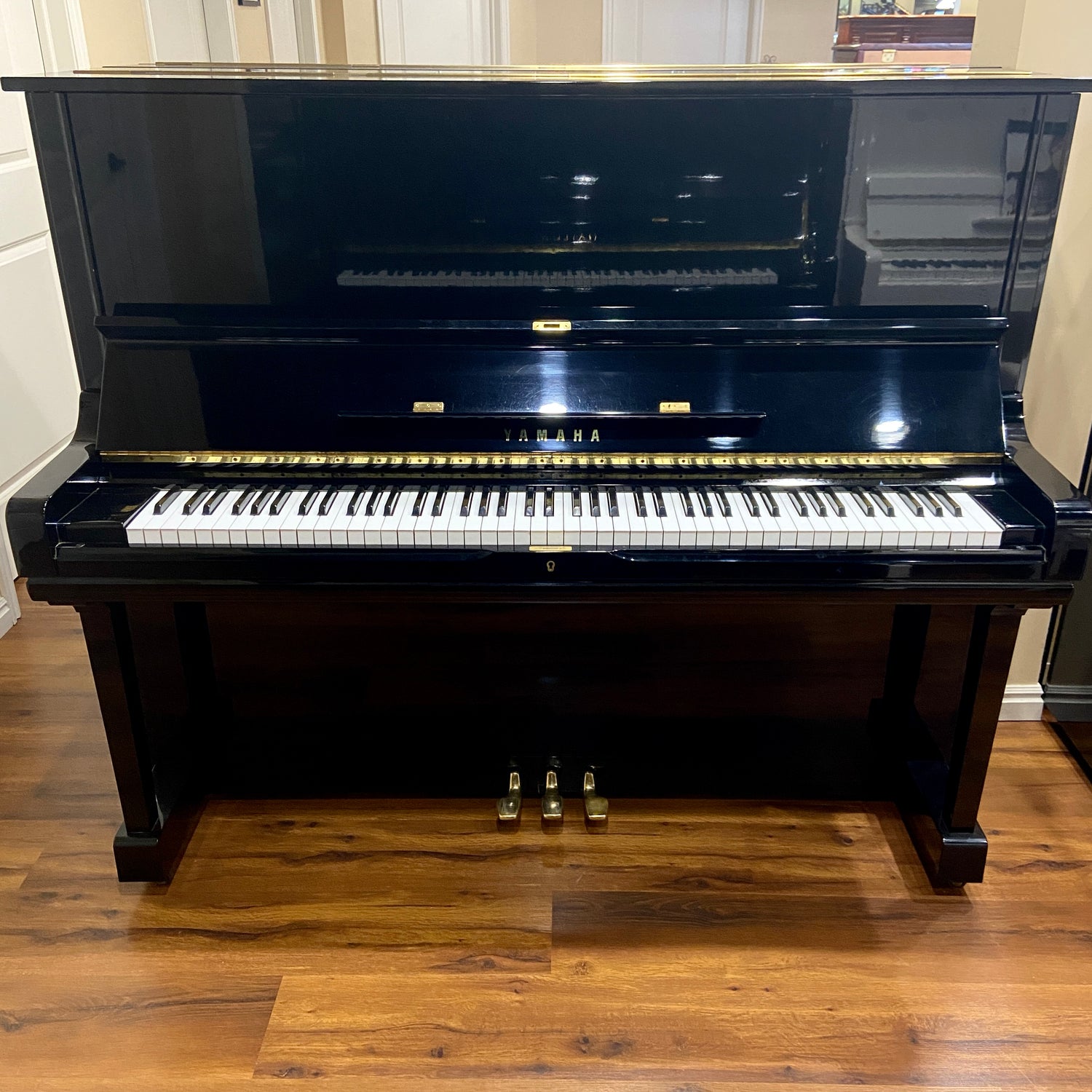 Polished Black Yamaha U3 upright piano on a wooden piano sales showroom floor