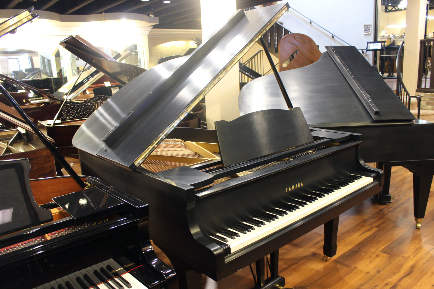 Yamaha G2 satin black finish Grand piano in a showroom setting with other pianos visible